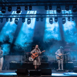 Das Bild zeigt eine Band auf der Bühne. Sie ist in blaues Licht und Nebel getaucht.