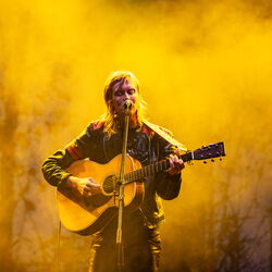 Anna Ternheim, steht in dichtem Nebel vor einem Mikrofon und spielt Gitarre. Sie wird mit warmen, gelben Licht angestrahlt.