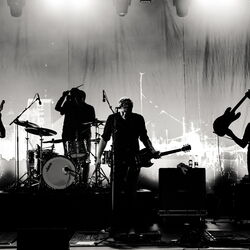 Schwarz-weiß Foto einer vierköpfigen Band von welcher durch die Belichtung nur die Silhouetten erkennbar sind.